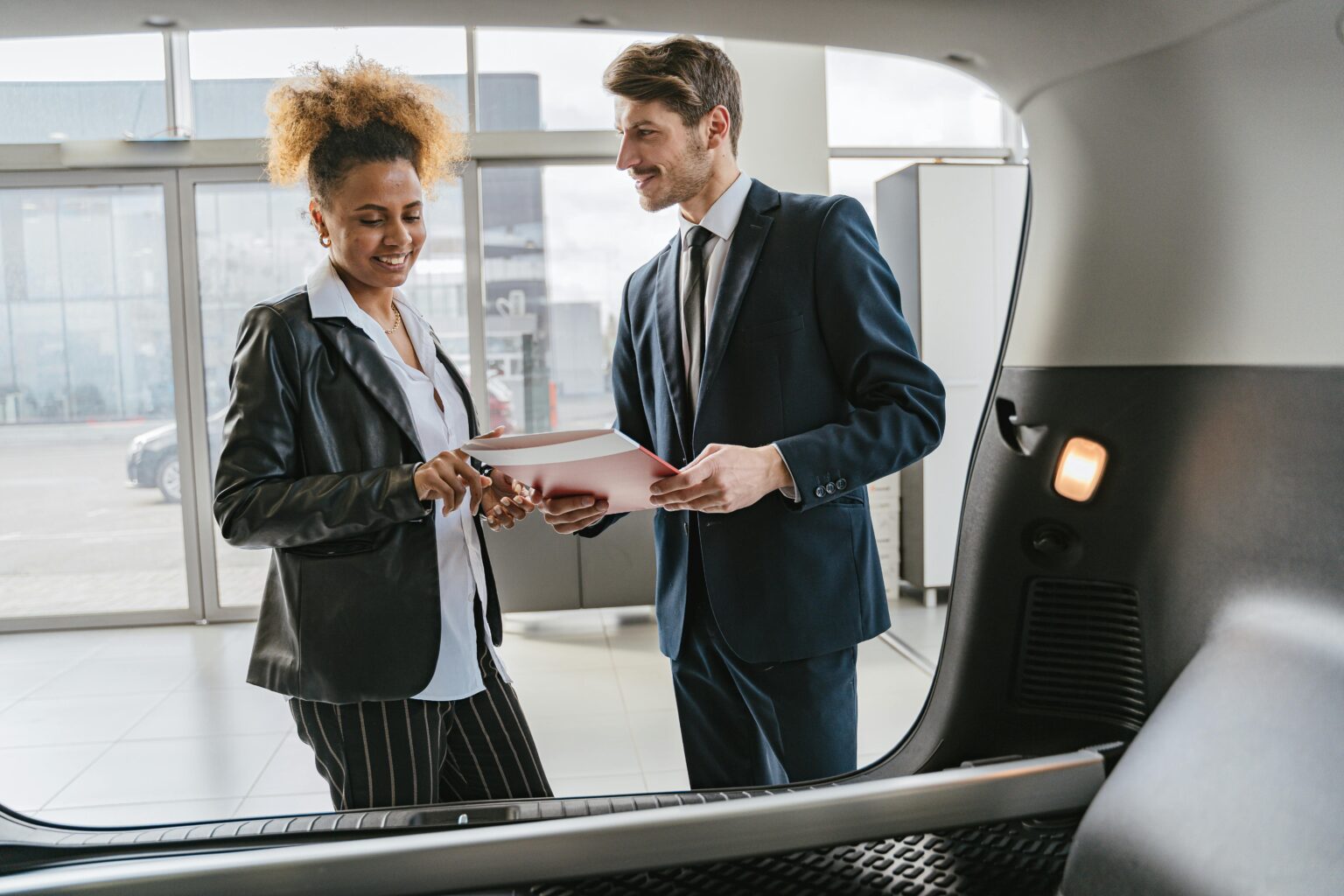 Small business owner discussing small business auto insurance with an insurance agent at a dealership