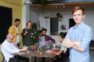 Young entrepreneur standing confidently in front of a collaborative team meeting—an inspiring example of how to start a CPA firm successfully in today’s business environment.