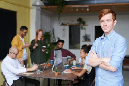 Young entrepreneur standing confidently in front of a collaborative team meeting—an inspiring example of how to start a CPA firm successfully in today’s business environment.